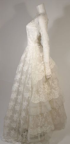 a white dress is on display in a glass case with a mannequin's head