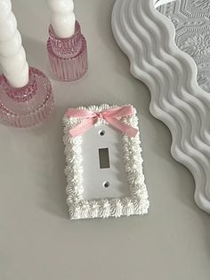 a white light switch cover sitting on top of a table next to candles and vases