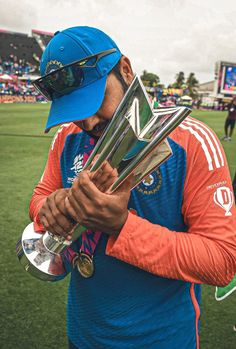 a man holding up trophies on top of a field