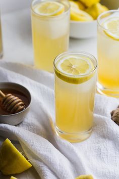 three glasses filled with lemonade and honey on top of a white towel next to sliced lemons