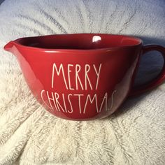 a red bowl with the words merry christmas written in white ink on it sitting on a bed