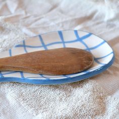 a wooden spoon sitting on top of a blue and white plate next to a cloth