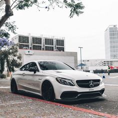 a white car is parked on the side of the road