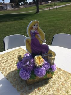 there is a table that has flowers and a princess figurine sitting on it