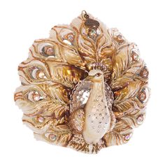 an ornament shaped like a peacock in gold and white with crystal eyes on it's back