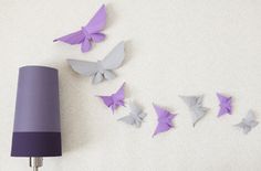 purple and grey butterflies are on the wall next to a lamp