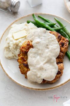 a white plate topped with meat patties covered in gravy and mashed potatoes