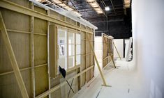 an unfinished room with wooden walls and windows in the process of being renovated by workers