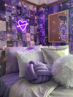 a bed with purple and white pillows in a room that has lights on the wall