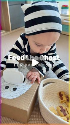 a small child wearing a hat and playing with food in a box on the floor