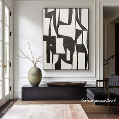 a large abstract painting hangs on the wall above a black and white couch in a living room