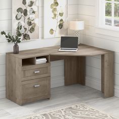 a computer desk with a laptop on top of it next to a window and rug