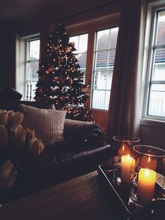 a living room filled with furniture and a christmas tree in the window sill next to it