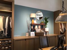 a desk with a lamp and some clothes on it in front of a blue wall