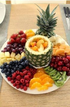 a white plate topped with lots of different types of fruit on top of a wooden table