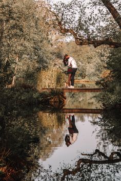 a person standing on a bridge over a body of water with trees in the background