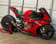 a red motorcycle parked in front of a garage door