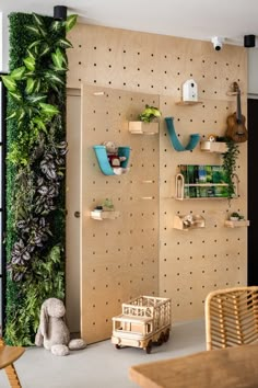 a living room filled with lots of green plants and shelves next to a wooden table