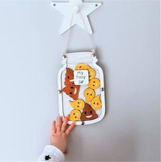 a child's hand reaching for a painted mason jar hanging from a star on the wall