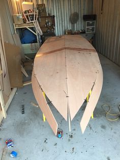 a wooden boat being built in a storage area with other tools and materials around it