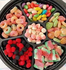 a black tray filled with lots of different colored candies next to other candy items