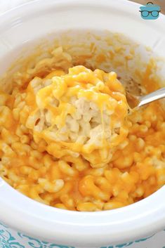 a spoon full of macaroni and cheese in a crock pot with the lid up