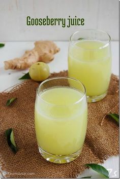 two glasses filled with juice sitting on top of a table