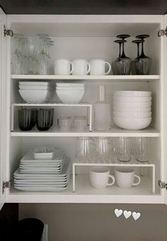 white dishes and cups are arranged on shelves