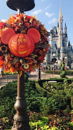 a pumpkin head on top of a lamp post in front of a disney world castle