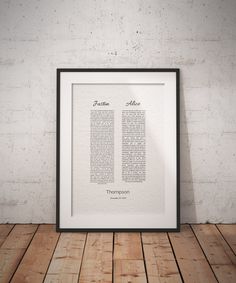 a framed print with the names of two different languages in black and white on a wooden floor