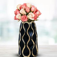 a black vase with pink and white roses in it