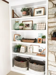 a white book shelf filled with baskets and pictures