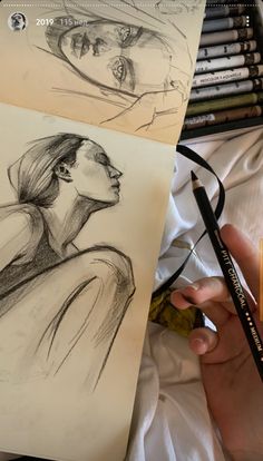 a person holding a pencil next to some drawings