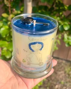 someone is holding a candle in their hand with a blue lid and black button on it