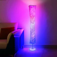 a floor lamp in the corner of a room with purple light coming from behind it