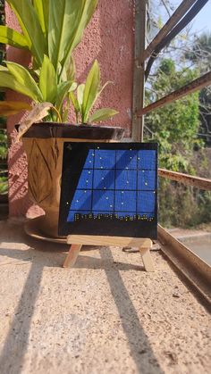 a small blue screen sitting on top of a wooden stand next to a potted plant