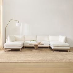 a white couch sitting on top of a wooden floor in a living room next to a lamp