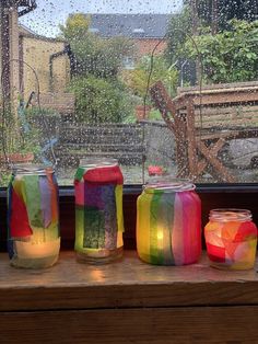 three jars filled with colorful liquid sitting on top of a window sill