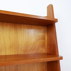 an empty wooden shelf against a white wall