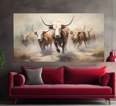 a living room with a red couch and painting on the wall above it that has three bulls running