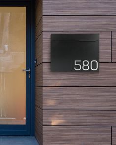 an address sign on the side of a building with a blue door and glass window