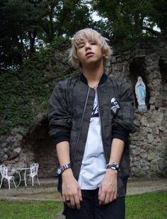 a young man standing in front of a stone wall with his hands on his hips