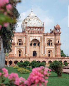 a large building with a white dome on top and pink flowers in the foreground