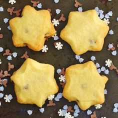 four star shaped cookies sitting on top of a pan covered in confetti flakes