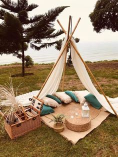 a teepee sitting on top of a lush green field next to the ocean with pillows and blankets