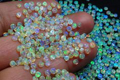 a hand is holding many small beads in it's palm, while the background shows blue and green holographics