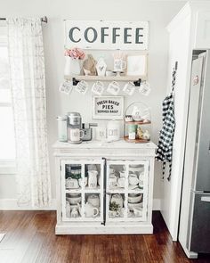 a kitchen with white walls and wooden floors, decorated with coffee signs on the wall