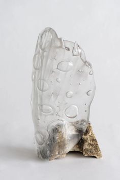 a piece of glass with water droplets on it and a rock in the foreground