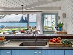 a kitchen with an island counter, sink and large window overlooking the ocean in front of it