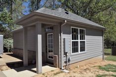 a small gray building sitting in the middle of a yard